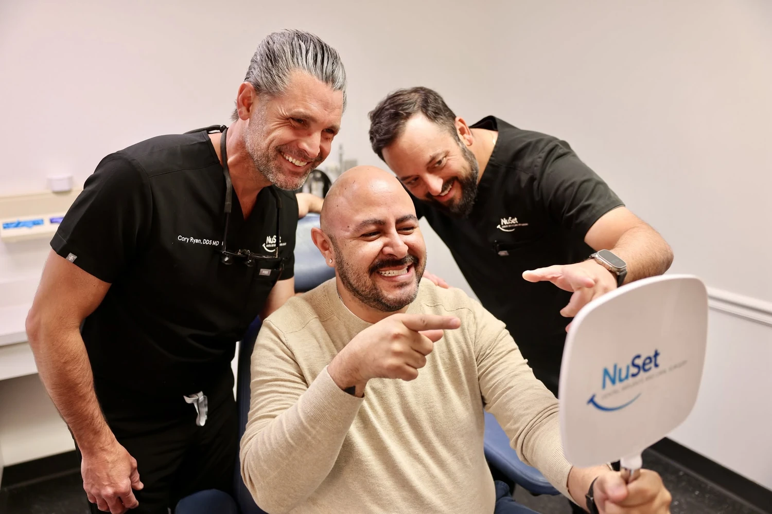 A NuSet surgeon and team member with a patient seeing his new smile for the first time.